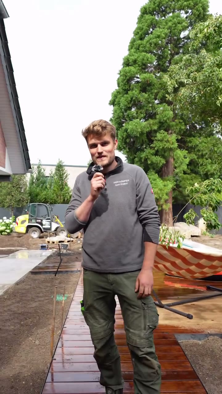 Ein Mitarbeiter mit Mikrofon erklärt das frisch verlegte Holzdeck an einem Pool in Verl.